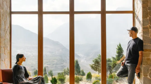 Guests relaxing in a lounge with large windows overlooking a scenic Mustang valley and mountains.