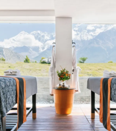 Two massage beds facing large windows with mountain views in a peaceful wellness center.