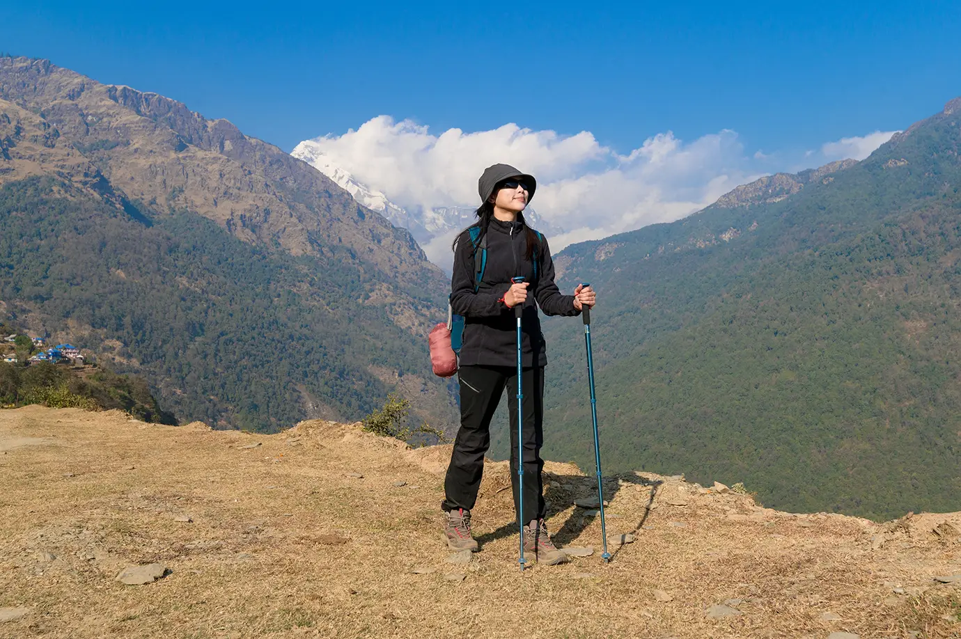 Solo female trekker hiking in Nepal mountains with trekking poles and scenic Himalayan backdrop