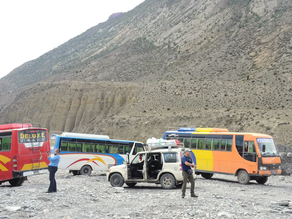 Group buses and a jeep crossing rugged terrain in Upper Mustang, showing the practical overland transport style often used on a standard Nepal tour.