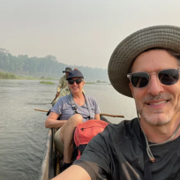 A smiling couple takes a selfie during a private dugout canoe ride on a river in Chitwan National Park, a central part of their Luxury Nepal Honeymoon Tour.