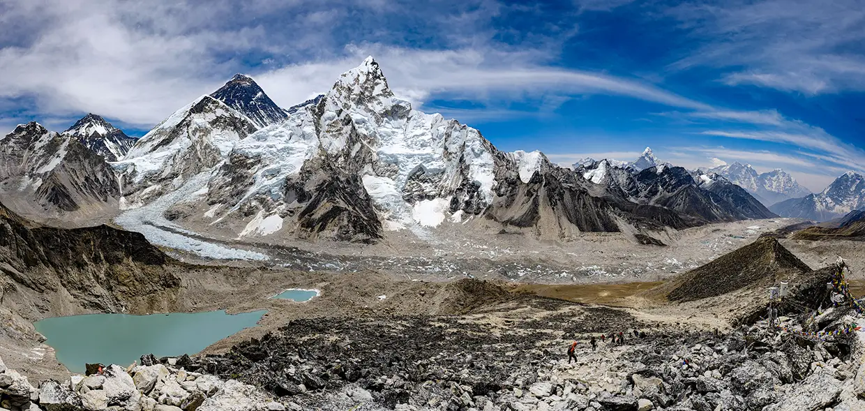 A sweeping panorama capturing the snow-capped peak of Ama Dablam rising dramatically above a deep, rugged Himalayan valley, viewed during a Luxury Everest Base Camp & Gokyo Lakes Trek.