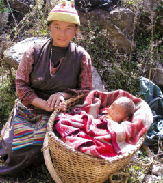 Local Himalayan woman sitting beside her baby in a basket during the Manaslu region trek in Nepal.
