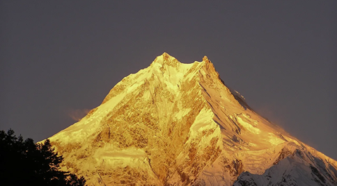 Golden sunset light shining on Mount Manaslu peak in the Himalayas of Nepal.
