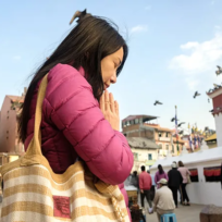 A woman in a pink jacket prays at the Boudhanath Stupa in Nepal. This spiritual experience is part of a Luxury Kathmandu Pokhara Tour.