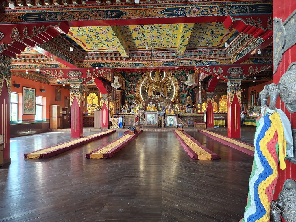 The colorful interior of temple in kopan monastery features ornate pillars and a golden Buddha statue, offering a serene atmosphere for a Kathmandu Luxury Experience.