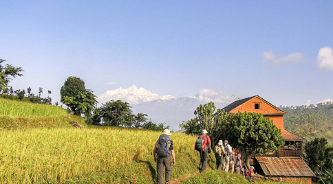 Traditional village and terraced fields during the Manaslu Circuit Trek in Nepal with mountain views in the background.