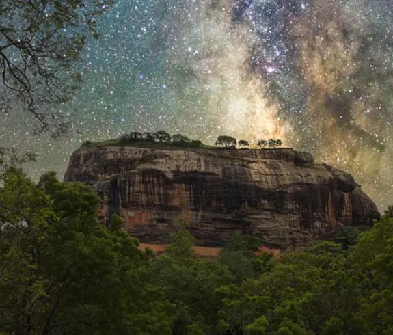 Sigiriya Itinerary is highlighted by a night sky filled with the Milky Way arching over the ancient Sigiriya Rock Fortress in Sri Lanka. Sri Lanka Itinerary