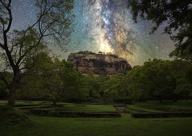Sri Lanka Itinerary features the ancient Sigiriya Rock Fortress rising above the jungle under a bright Milky Way starry night sky.
