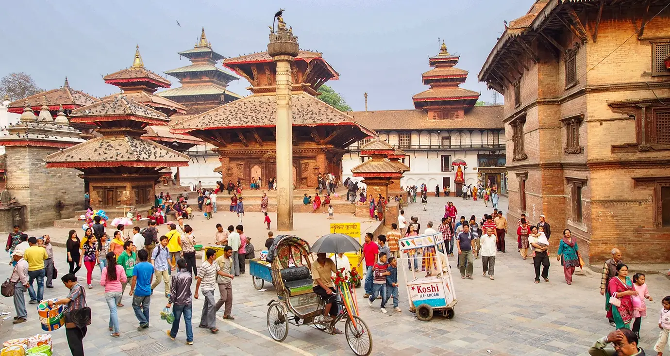 Things to do in Kathmandu features a crowded historic square filled with ancient temples, traditional Newari buildings, and a cycle rickshaw.