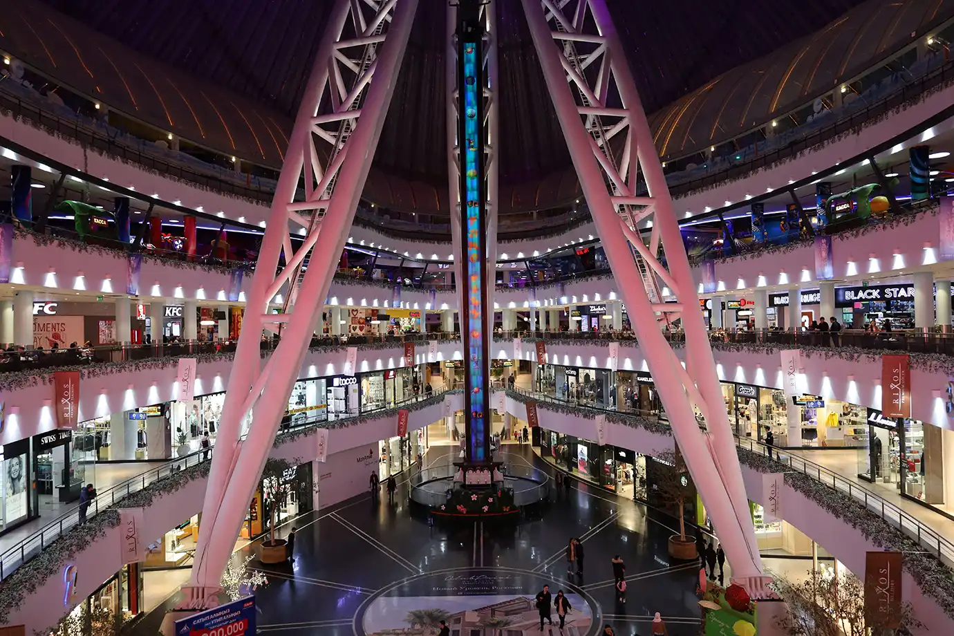 A large air-conditioned indoor shopping mall atrium featuring multiple retail levels and a central amusement drop tower, featured in Best Time to Visit Dubai.