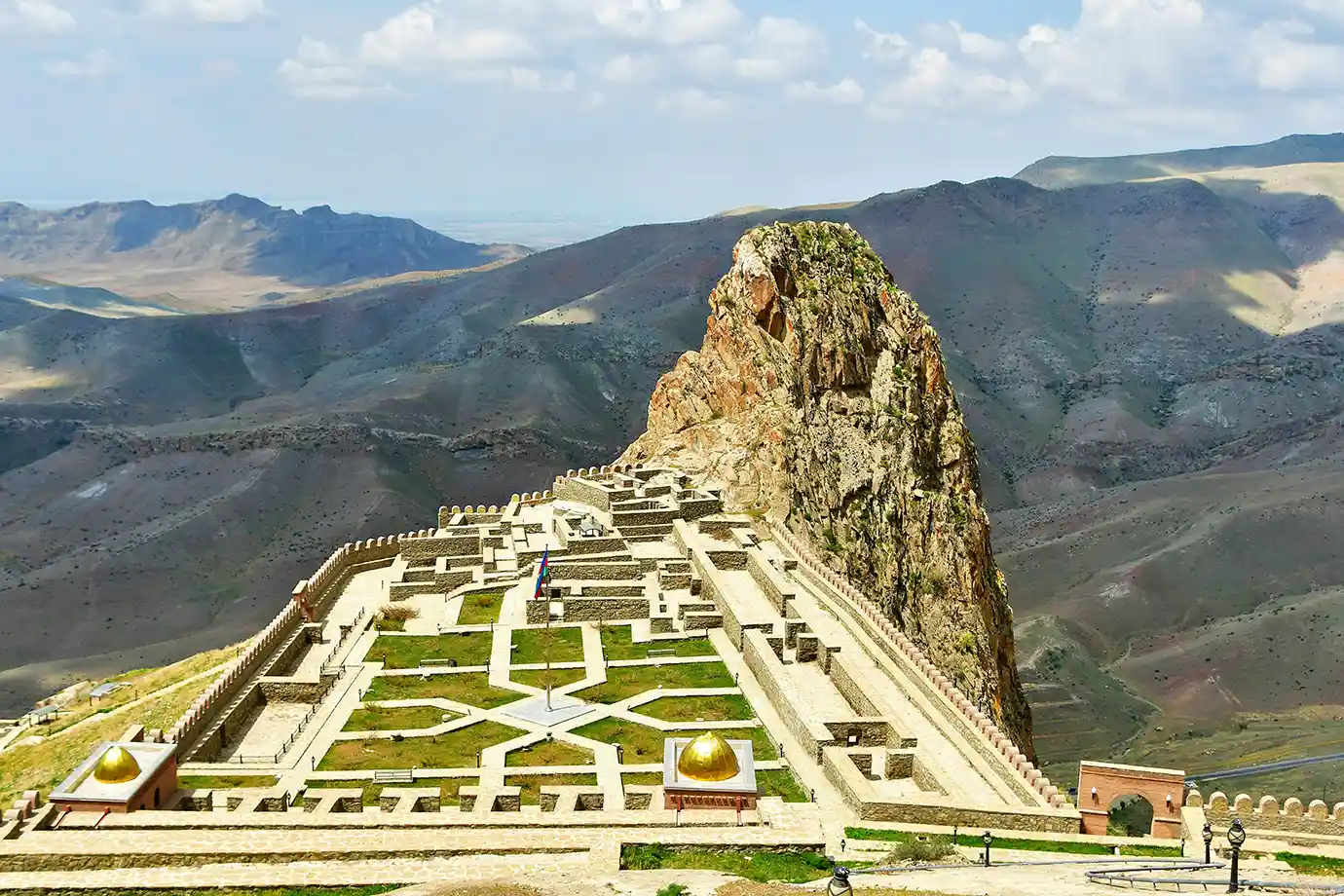 An aerial-style view of the restored courtyards, golden-domed structures, and towering rock crag of Alinja Castle featured in a travel guide on 5 Must-Visit Destinations in Azerbaijan Beyond Baku.