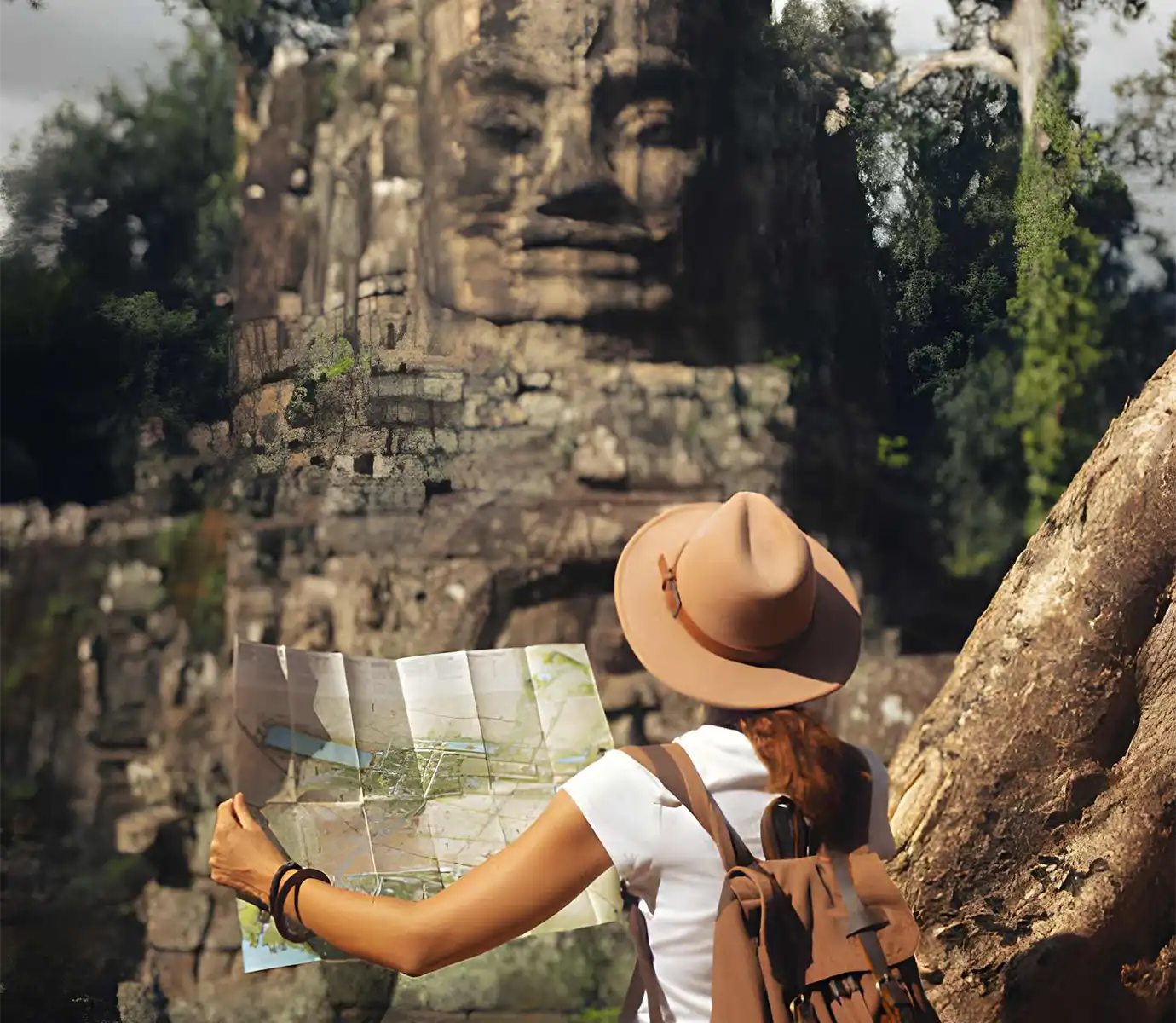 A woman in a sunhat holding a paper tourist map in front of a giant carved stone face tower in the Angkor Archaeological Park featured in a travel guide on Angkor Wat Tickets.