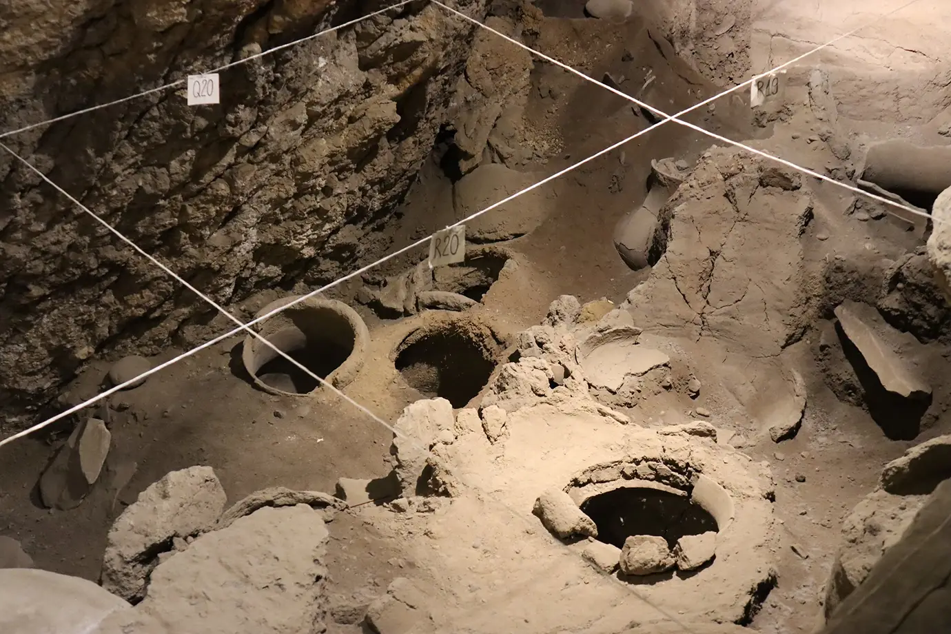 Large ancient clay storage jars embedded in the ground at the Areni-1 cave excavation site featured in a culinary guide on What to Eat in Armenia.