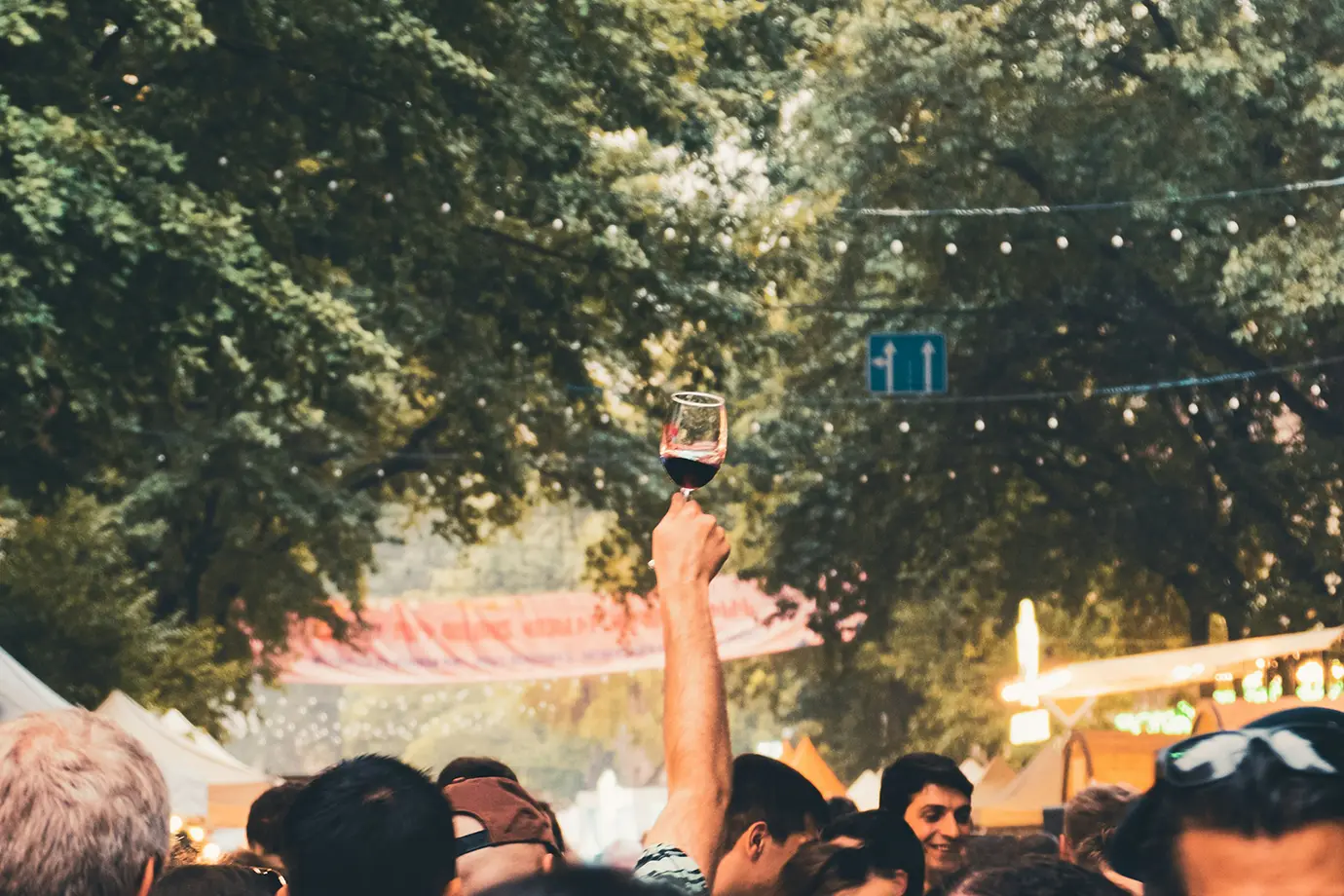 A attendee holding up a wine glass filled with red wine amidst a lively crowd during the autumn Areni Wine Festival featured in a travel guide on When Is the Best Time to Visit Armenia.