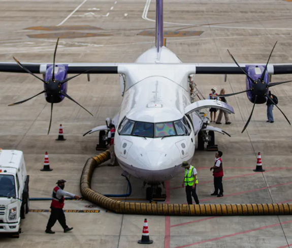A white passenger aircraft parked on an airport tarmac with ground crew servicing the flight featured in a travel guide on Cambodia Visa Requirements.