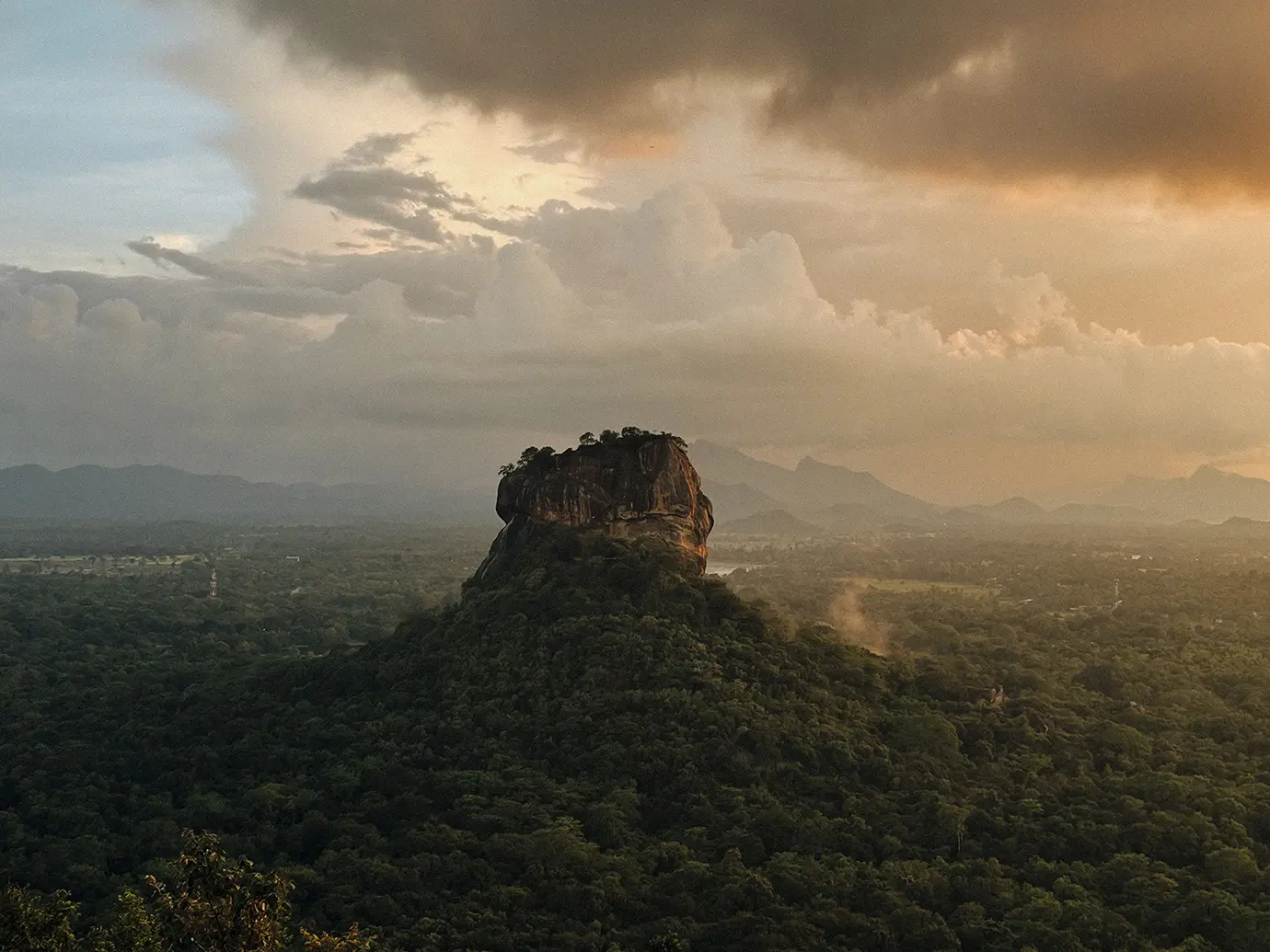 Aerial view of Sigiriya Rock fortress surrounded by lush forests during a dramatic sunset, featured in the Sri Lanka and Maldives Travel Guide