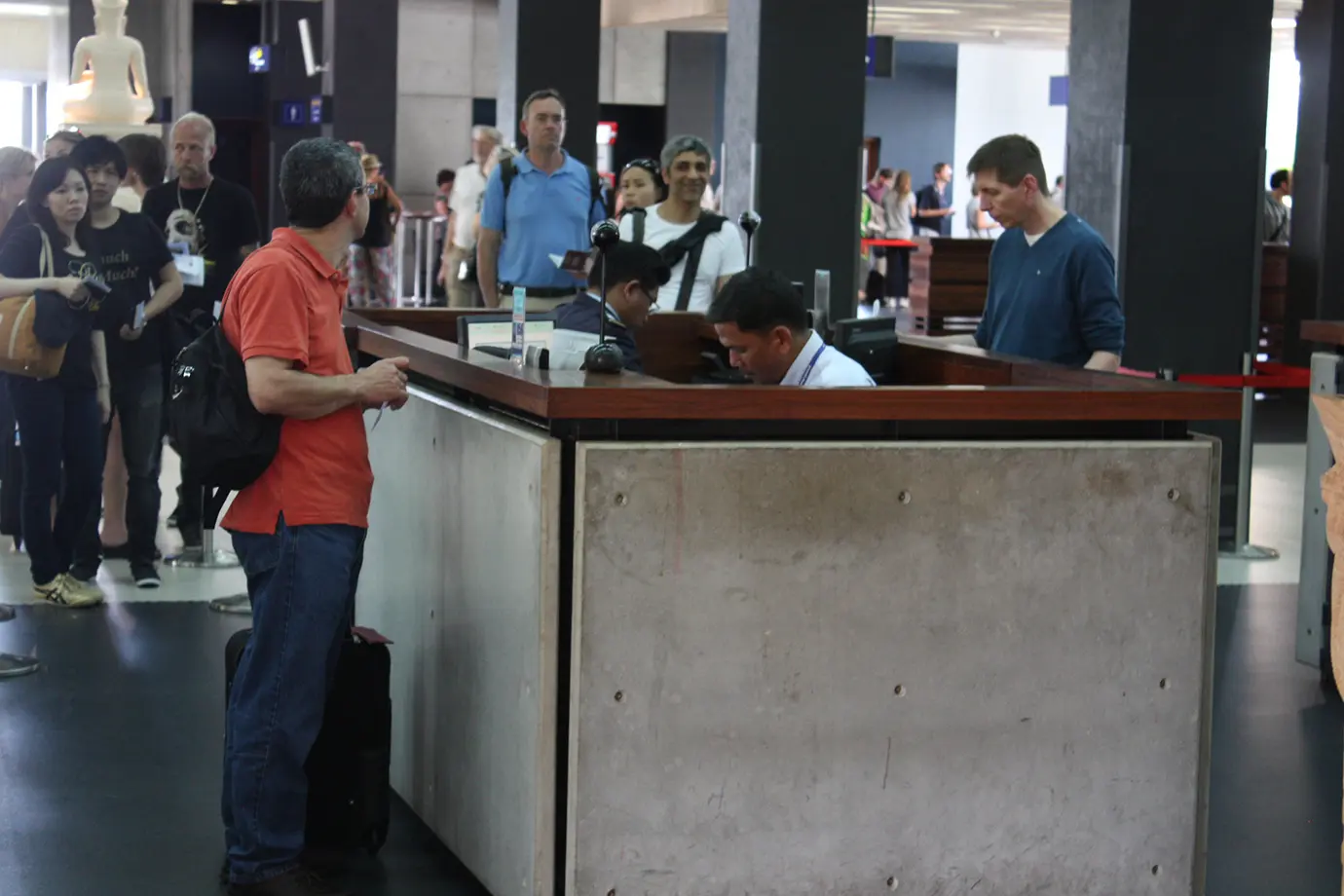 International passengers standing in line at an airport passport control and immigration desk featured in a travel guide on Cambodia Visa Requirements.