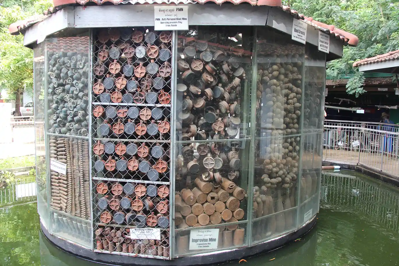 A glass display casing filled with disarmed landmines, grenades, and ordnance at the Cambodia Landmine Museum featured in a guide on Things to Do in Siem Reap Beyond Angkor Wat.