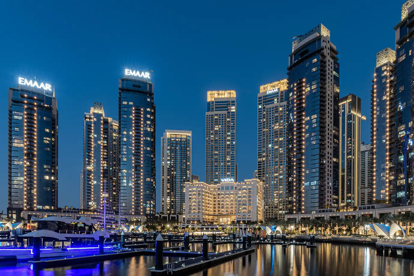 A serene twilight view of lit-up modern luxury towers and yacht docks along Dubai Marina, showcasing evening Things to Do in Dubai.
