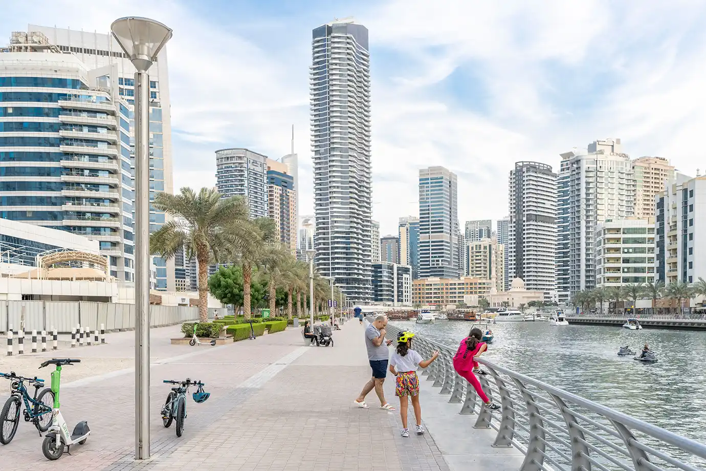 A family enjoying a scenic walk along the waterfront promenade at Dubai Marina, an ideal destination when exploring Dubai with Kids.