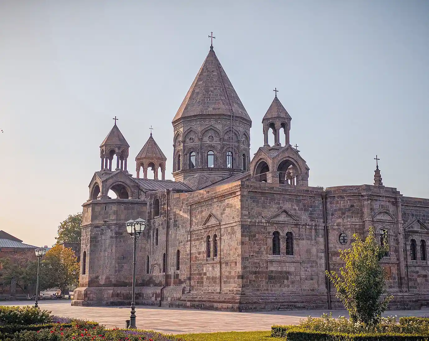 The ornate stone exterior and pointed domes of Etchmiadzin Cathedral standing under a clear sky featured in a travel guide on 5 Must-See Monasteries in Armenia.