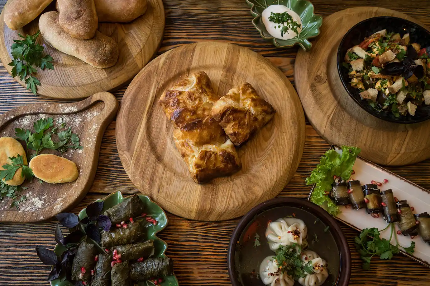 An overhead view of a table spread featuring traditional khachapuri, dolma, khinkali, and eggplant rolls, illustrating daily dining expenses for Georgia Travel Cost.