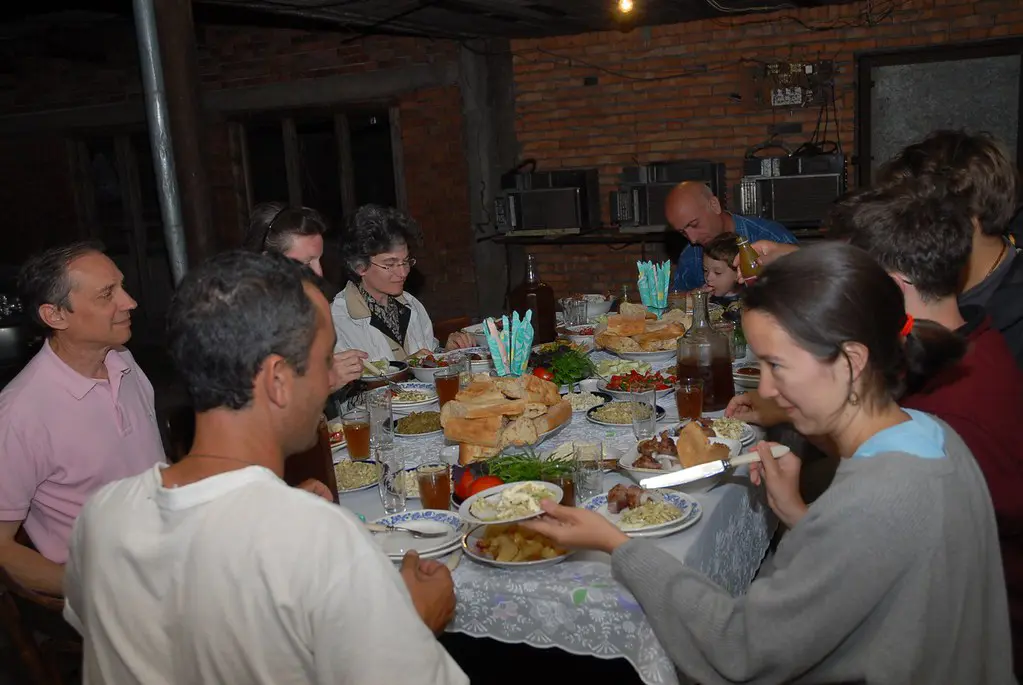 A group of people sitting around a long table packed with traditional dishes and house wine during a traditional supra feast, highlighting culture for a Georgian Food Guide.