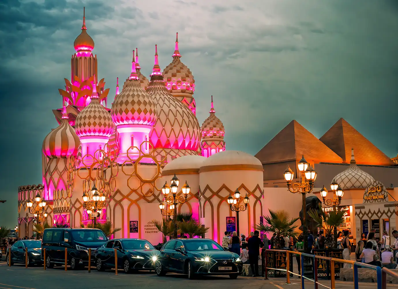 Pink-lit ornate Russian-style domes standing beside Egyptian pyramid structures at Global Village Dubai during twilight, featured in Best Time to Visit Dubai.