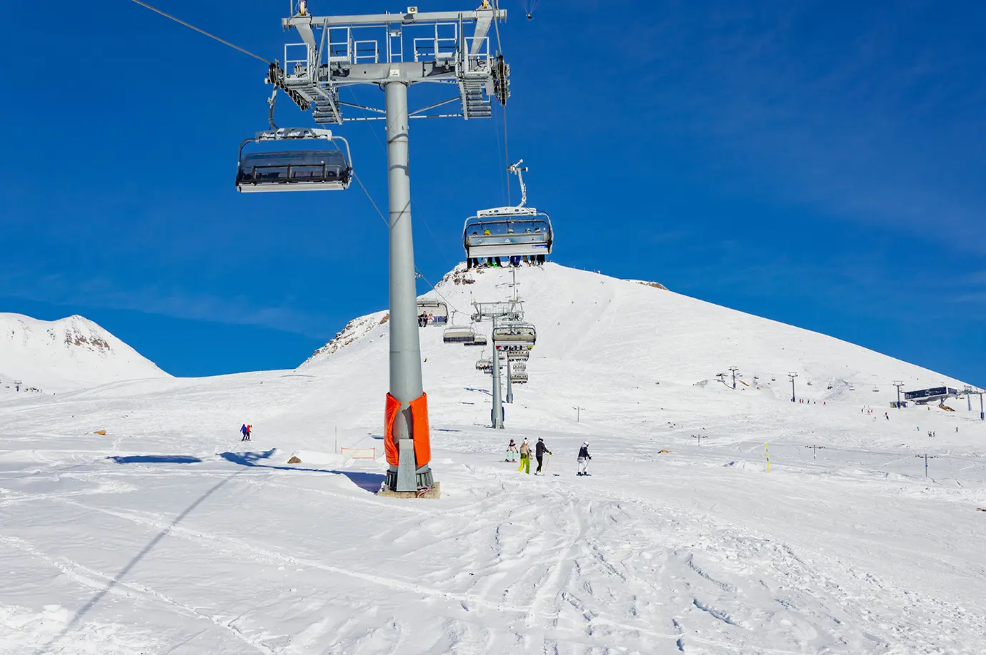 A tall metal chairlift pylon operating over powdery snow fields under a clear blue sky at Gudauri Ski Resort, illustrating the Best Time to Visit Georgia.