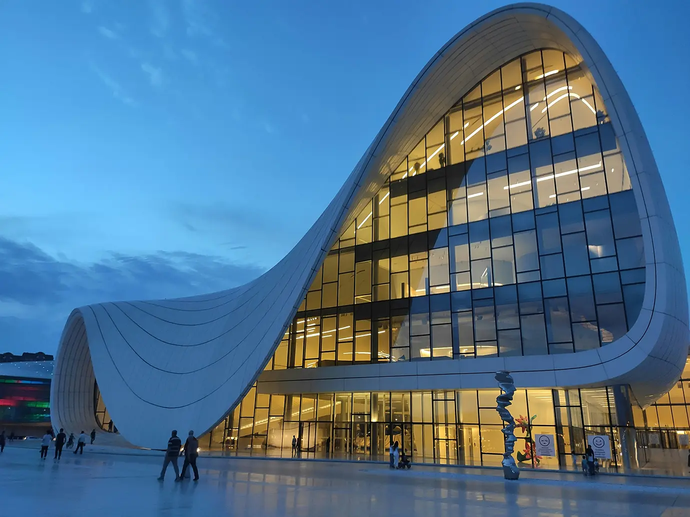 The flowing white curves and illuminated glass facade of the Heydar Aliyev Center at twilight featured in a travel guide on The Ultimate 7-Day Azerbaijan Itinerary.