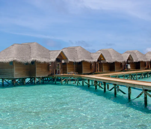 Overwater bungalows connected by wooden boardwalks over clear turquoise water featured in The Ultimate Sri Lanka and Maldives Travel Guide.
