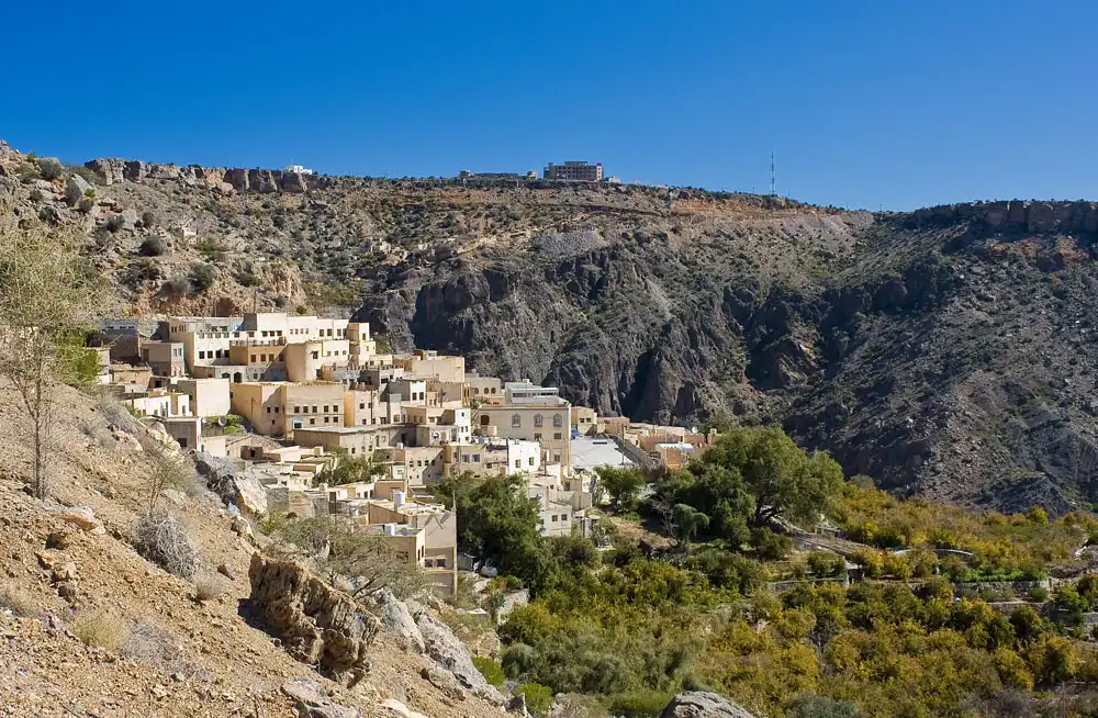 Traditional mountain village nestled into the rugged slopes of Jebel Akhdar featured in an Oman and Maldives Travel Guide.