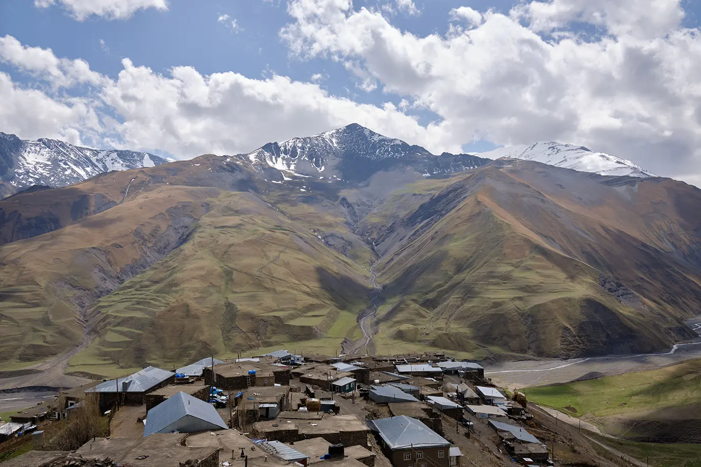 The ancient stone village of Khinaliq perched on a mountain ridge below towering snow-dusted peaks featured in a travel guide on 5 Must-Visit Destinations in Azerbaijan Beyond Baku.