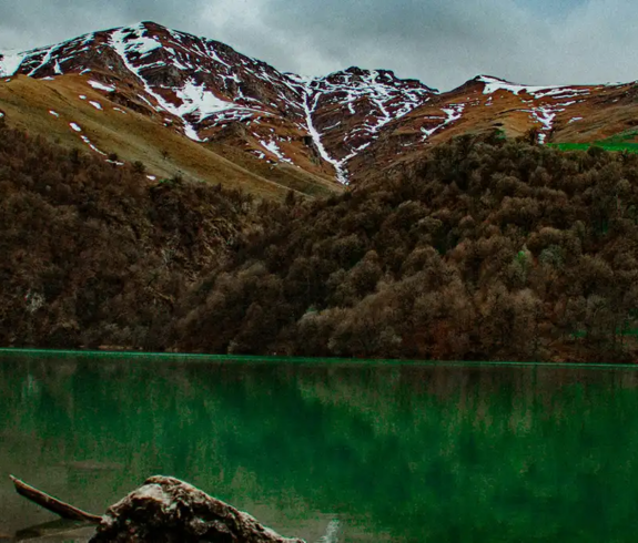 The deep green alpine waters of Lake Goygol reflecting dense surrounding forests and snow-capped mountain peaks featured in a travel guide on 5 Must-Visit Destinations in Azerbaijan Beyond Baku.