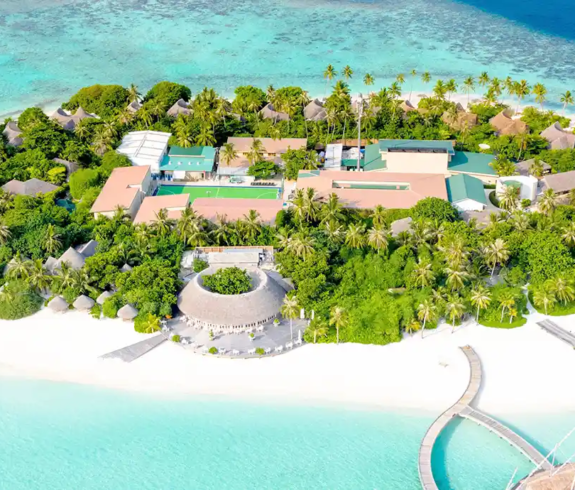 A panoramic aerial view of a tropical island resort with white sandy beaches and clear turquoise lagoons featured in a travel guide on the Best Time to Visit the Maldives.