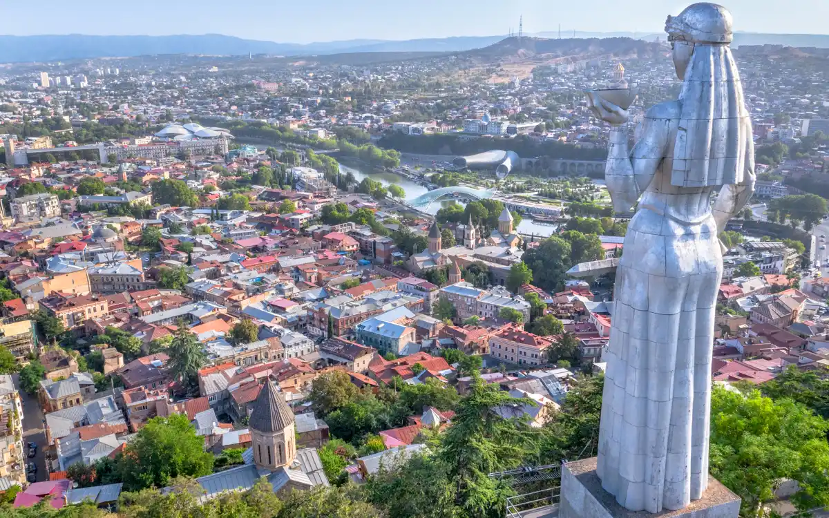 The back profile of the aluminum Mother of Georgia statue holding a wine cup while overlooking the vast cityscape of Old Tbilisi, highlighting iconic Things to Do in Tbilisi.