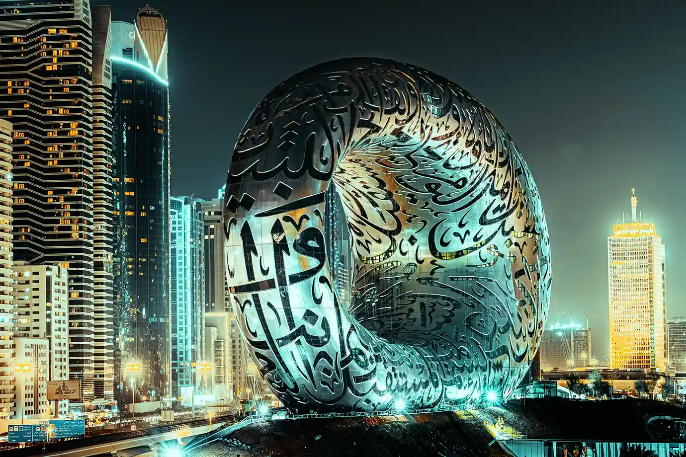 The metallic, Arabic calligraphy-covered torus structure of the Museum of the Future at night, a key landmark when exploring Things to Do in Dubai.