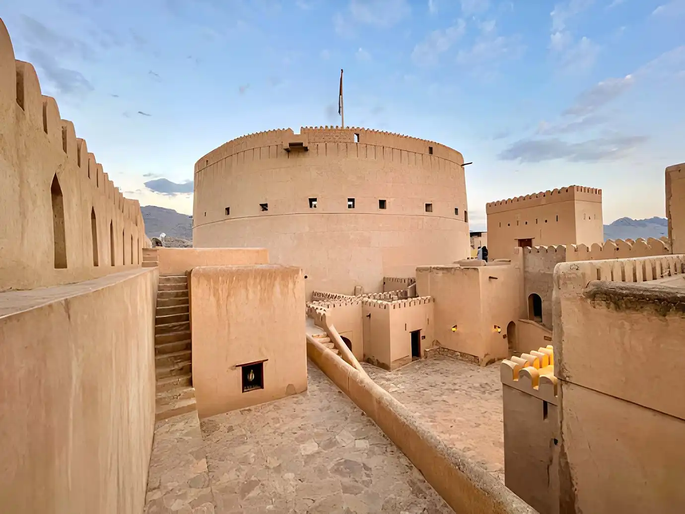 Courtyard and massive circular stone tower of Nizwa Fort featured in an Oman and Maldives Travel Guide.