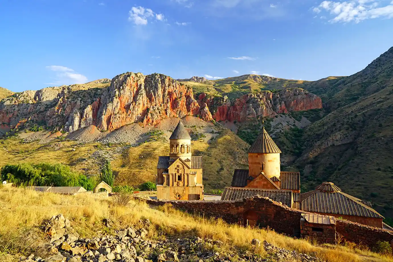 The stone churches of Noravank Monastery nestled in a canyon surrounded by towering red rock cliffs featured in a travel guide on The Ultimate 7-Day Armenia Itinerary.