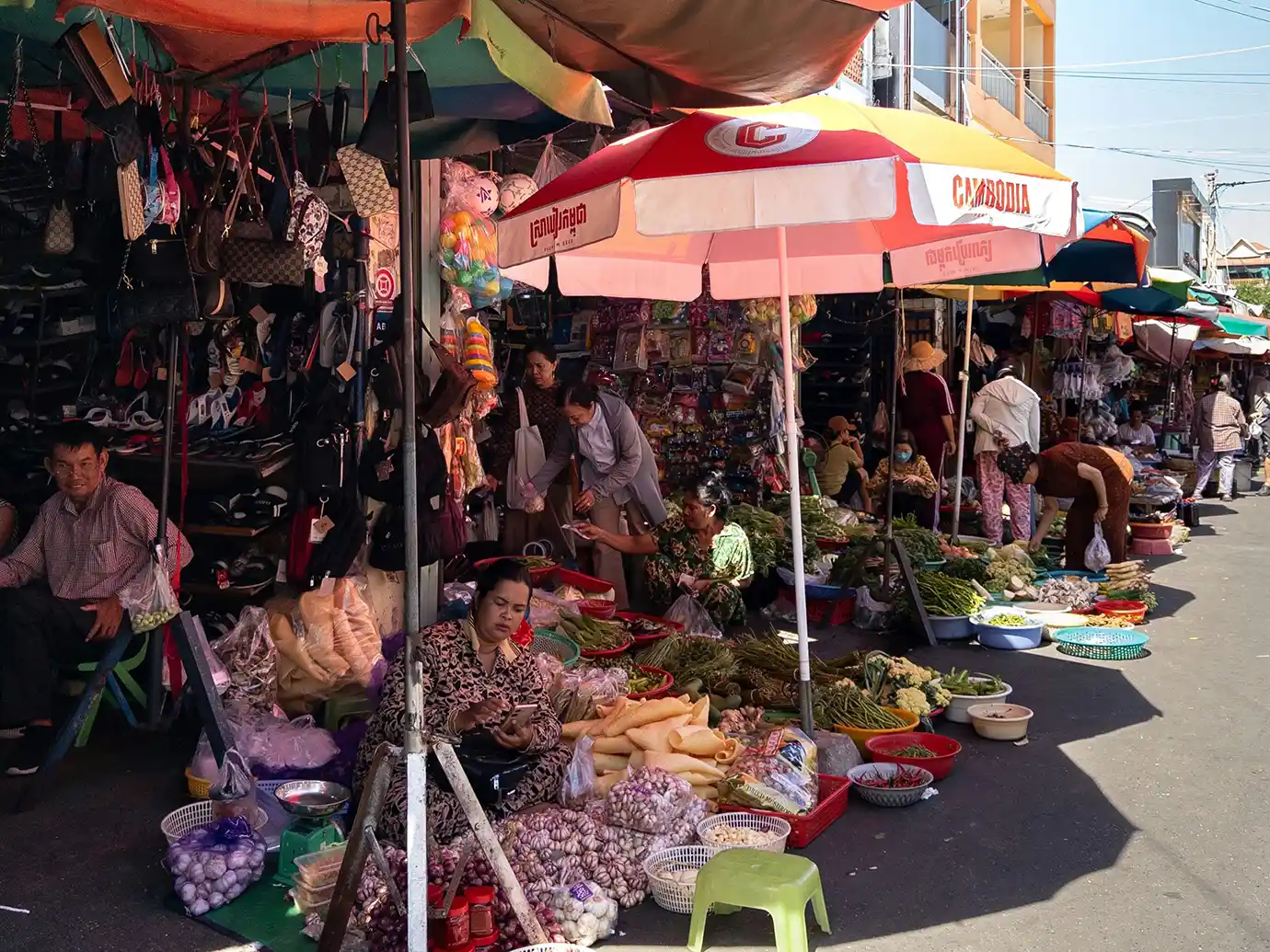 Local Cambodian vendors selling fresh produce, garlic, and goods under colorful parasols at the Old Market featured in a guide on Things to Do in Siem Reap Beyond Angkor Wat.