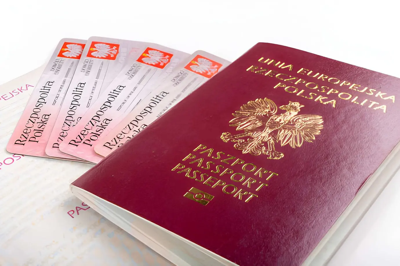 A burgundy Polish European Union passport laying beside stacked residence permit cards, illustrating essential entry documents for Dubai Visa Requirements.