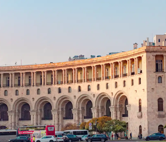 Grand neoclassical Government Building crafted from pink tuff stone lining Republic Square featured in a travel guide on Best Things to Do in Yerevan Armenia.