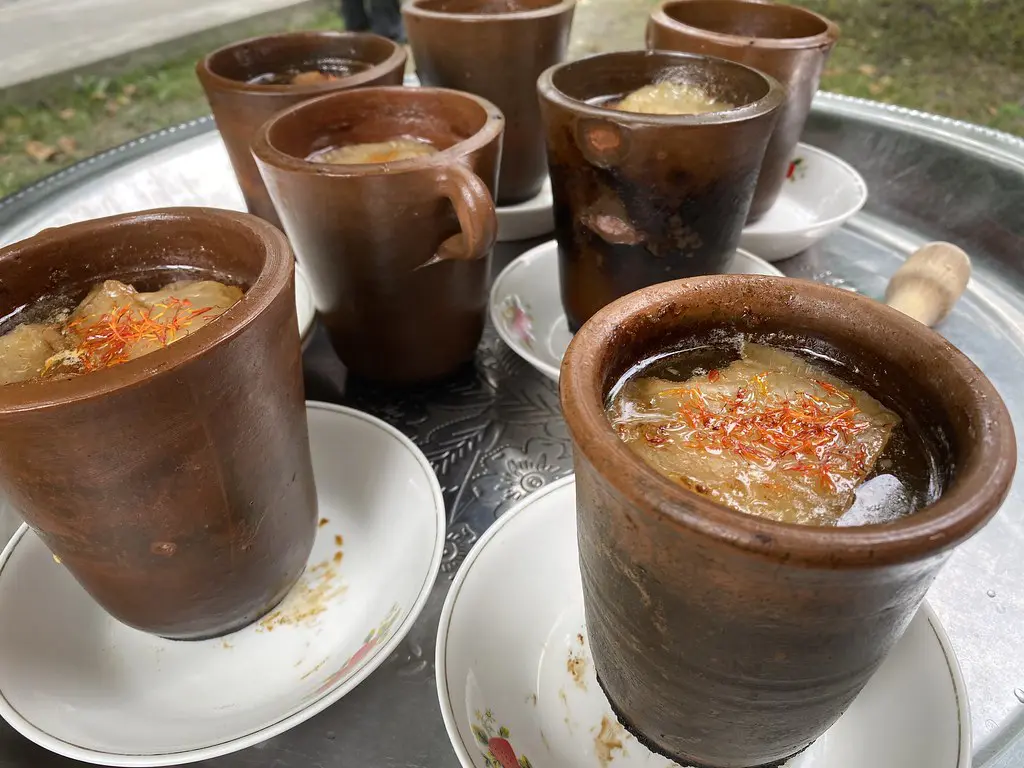 Earthenware clay pots filled with rich lamb and chickpea piti stew topped with saffron strands on a tray featured in a travel guide on What to Eat in Azerbaijan.