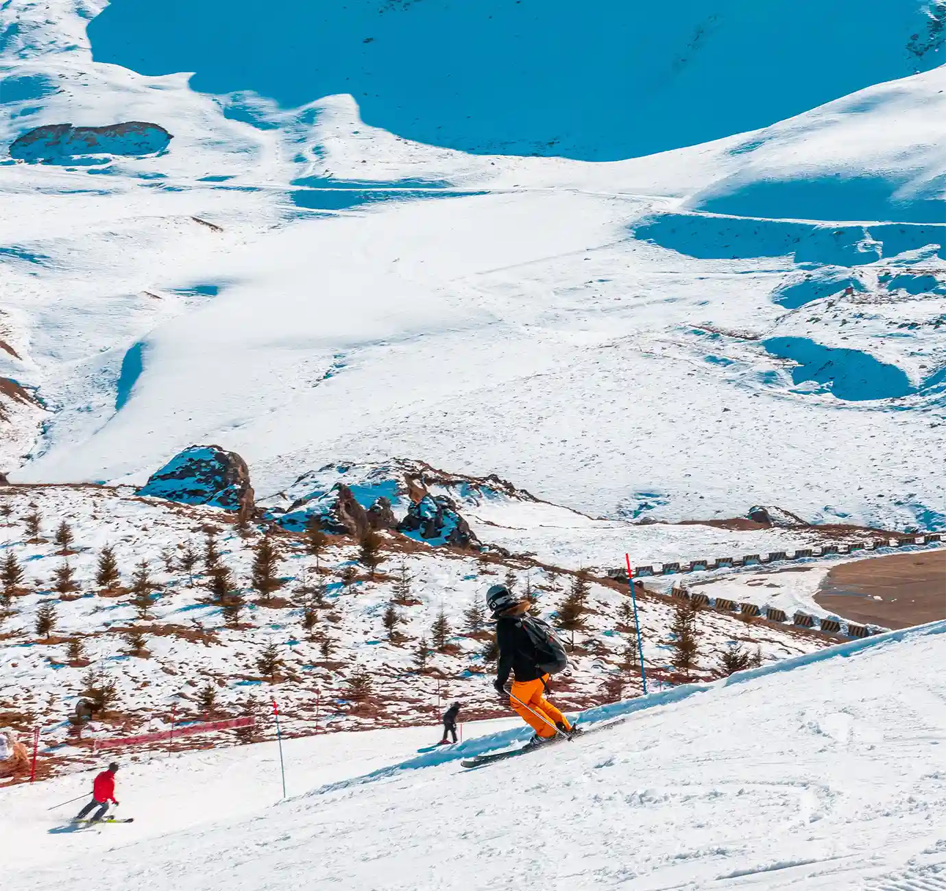 A skier in bright orange pants gliding down a snow-covered slope surrounded by snow-capped Greater Caucasus peaks featured in a travel guide on When Is the Best Time to Visit Azerbaijan.