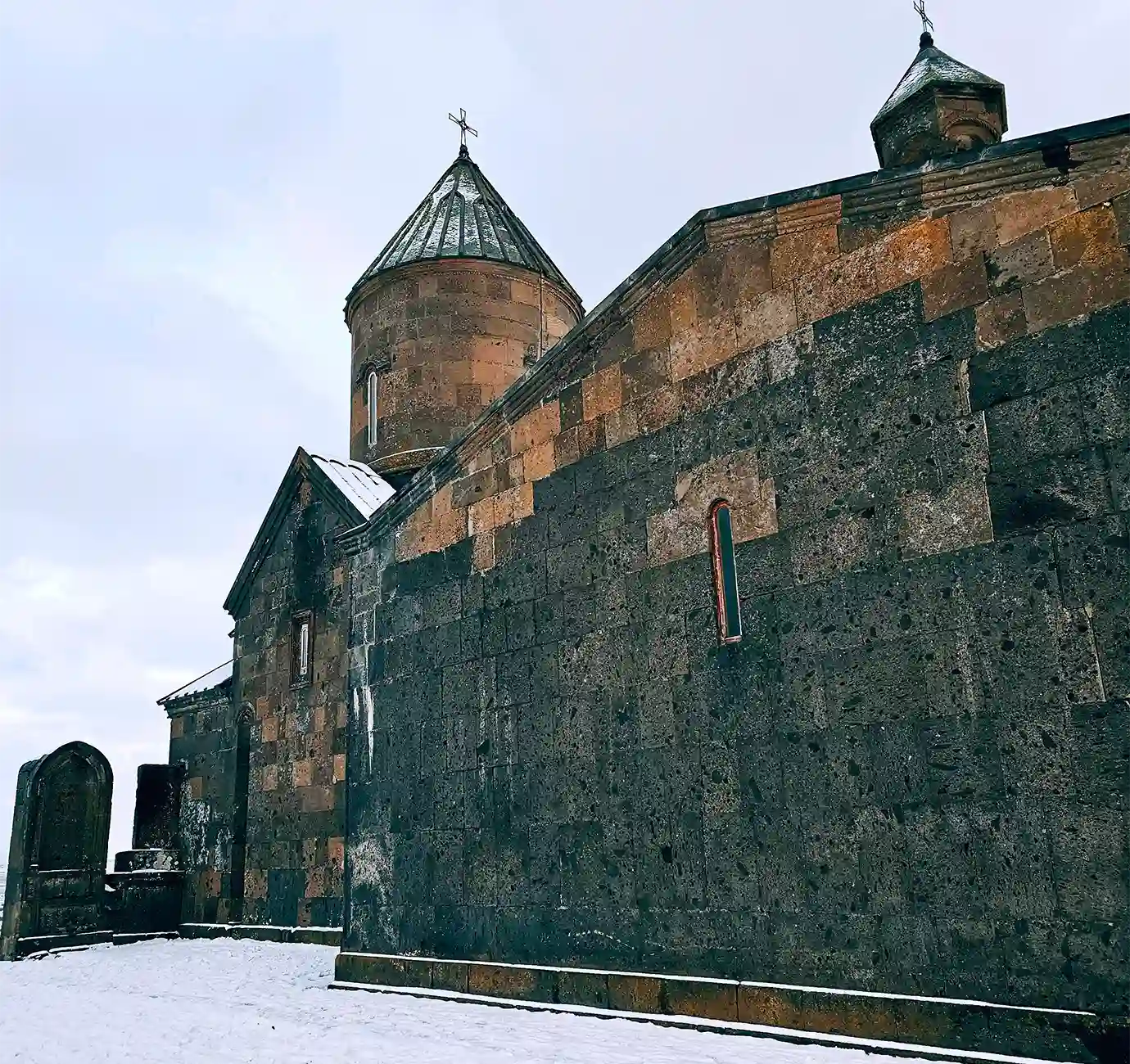 Snow dusting the stone walls and conical dome of Hovhannavank Monastery featured in a travel guide on When Is the Best Time to Visit Armenia.