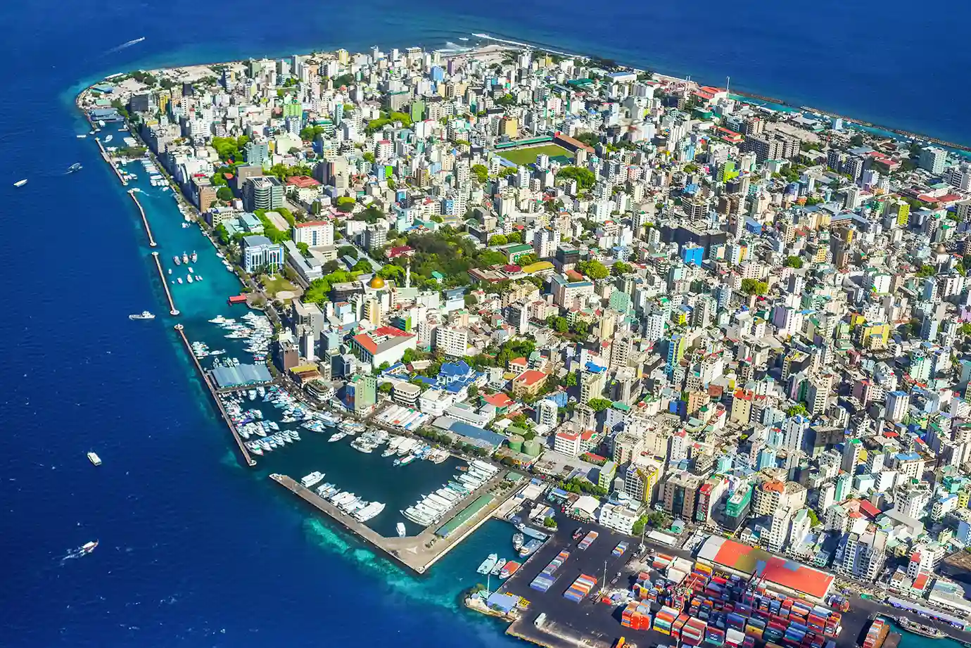 High-angle aerial panorama of colorful high-rise buildings and harbors in Malé featured in a Maldives Travel Guide for First-Timers.