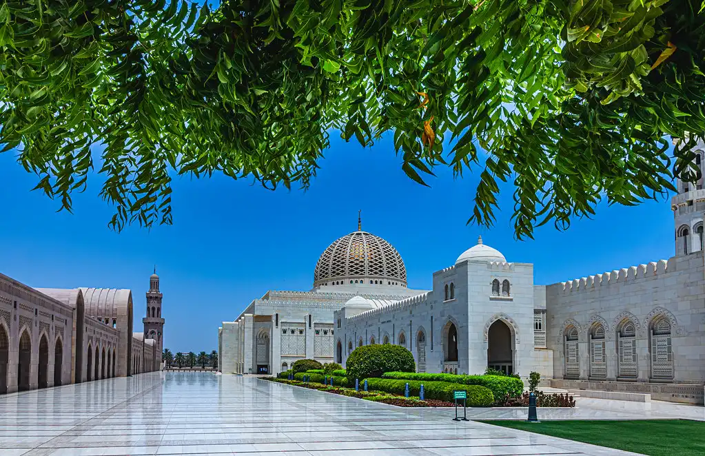 White marble courtyard and grand central dome of Sultan Qaboos Grand Mosque featured in an Oman and Maldives Travel Guide.