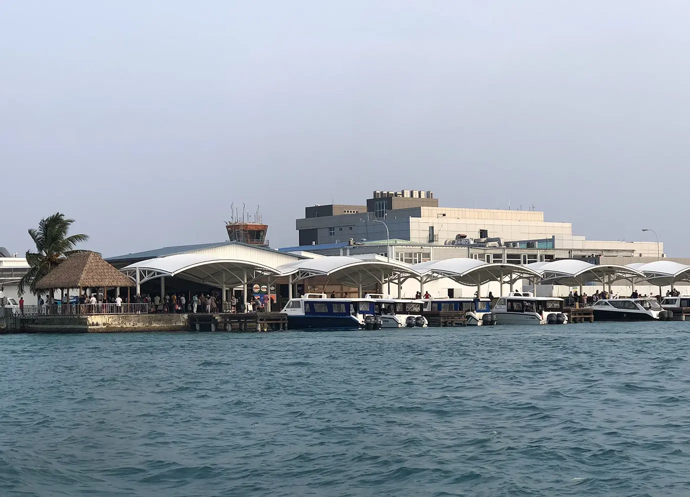 Speedboats docked along the covered passenger docks at Velana International Airport featured in a Maldives Travel Guide for First-Timers.
