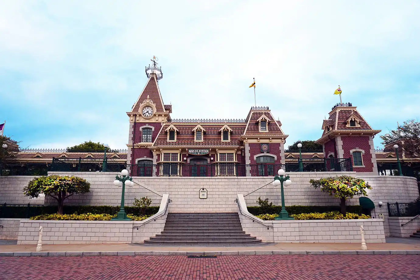 The Victorian-style Main Street Station building with a clock tower and grand stone stairs, featured in a Hong Kong Disneyland Guide.